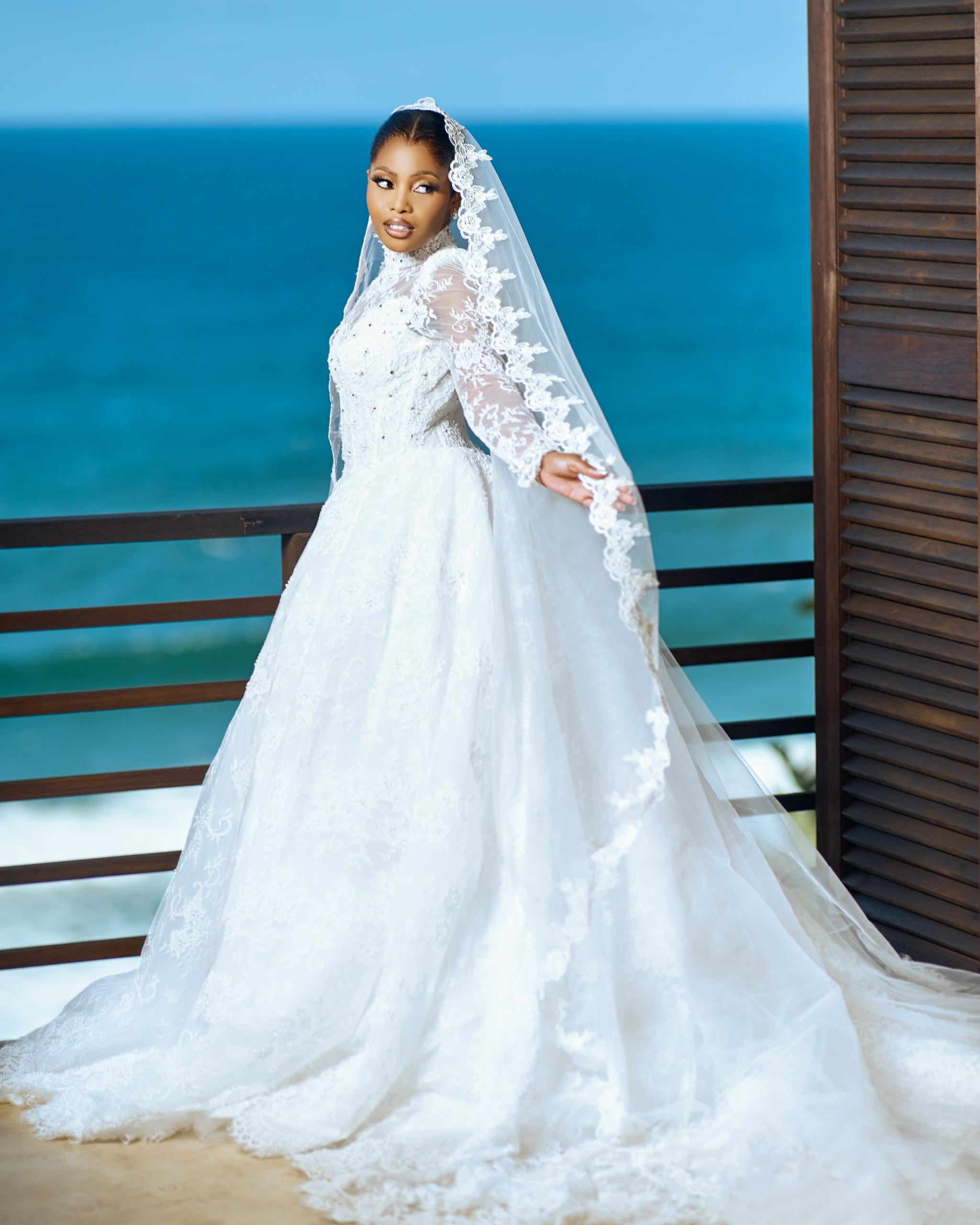 Bride in her wedding dress and veil overlooking the sea.