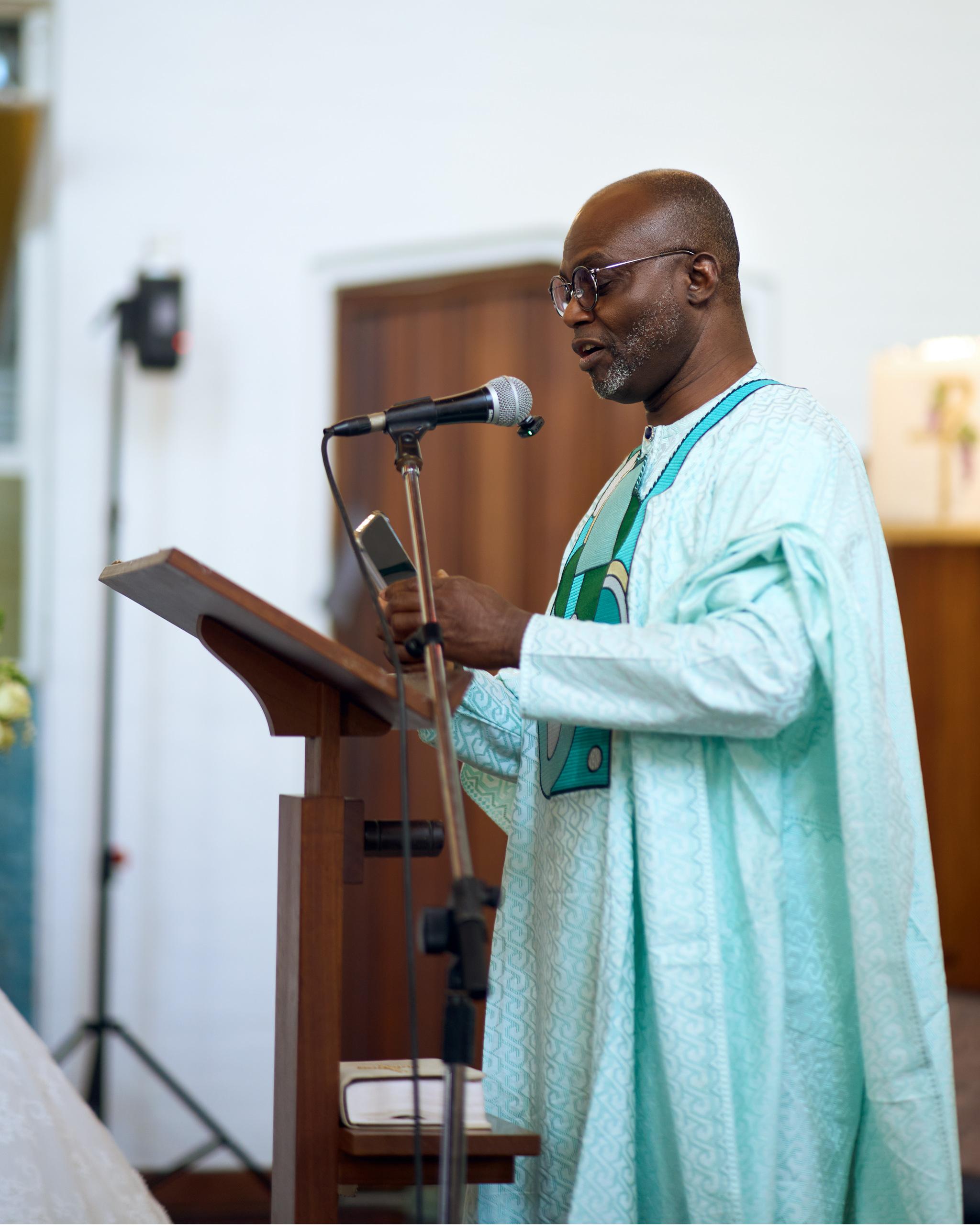 Minister in green vestments speaking at the church lectern.