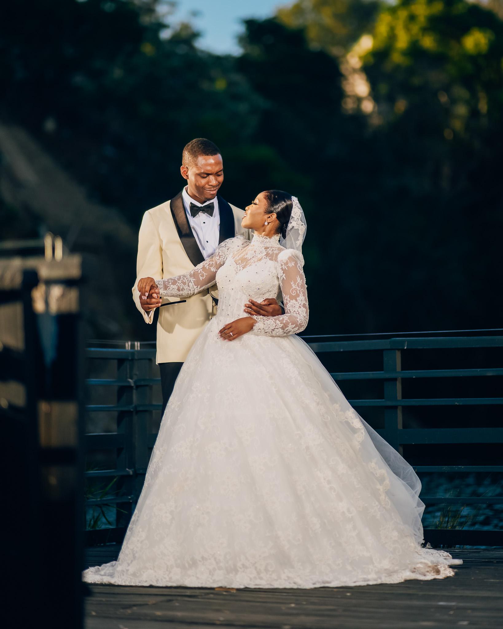 Bride and groom holding hands and smiling as they dance.