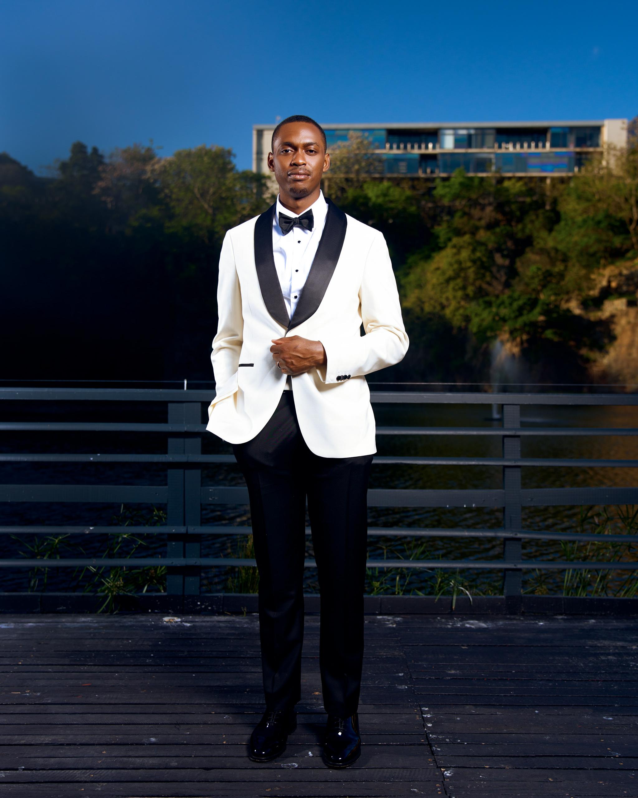 Groom in a white dinner jacket on an outdoor terrace.