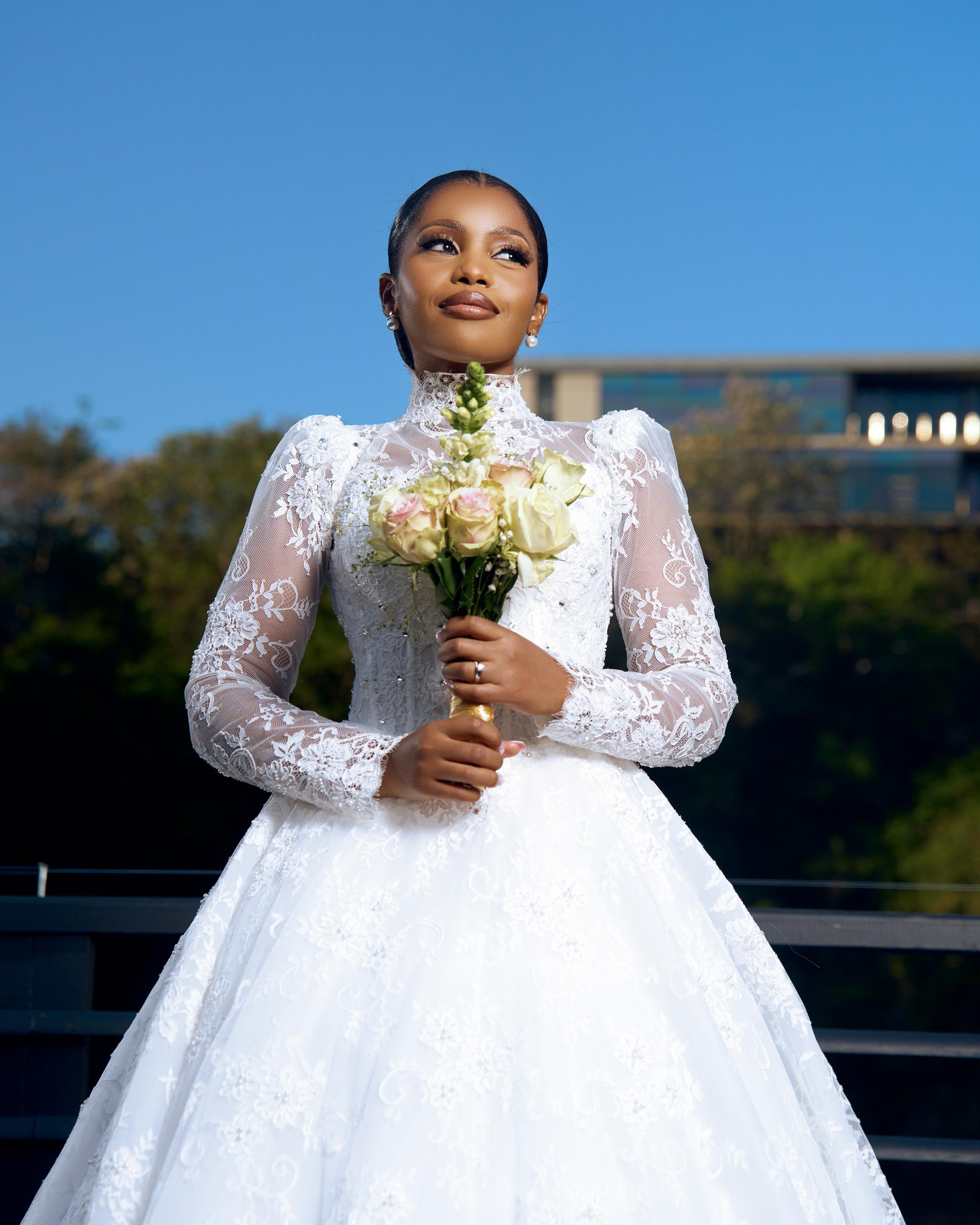 Bride holding her bouquet beneath a bright blue sky.