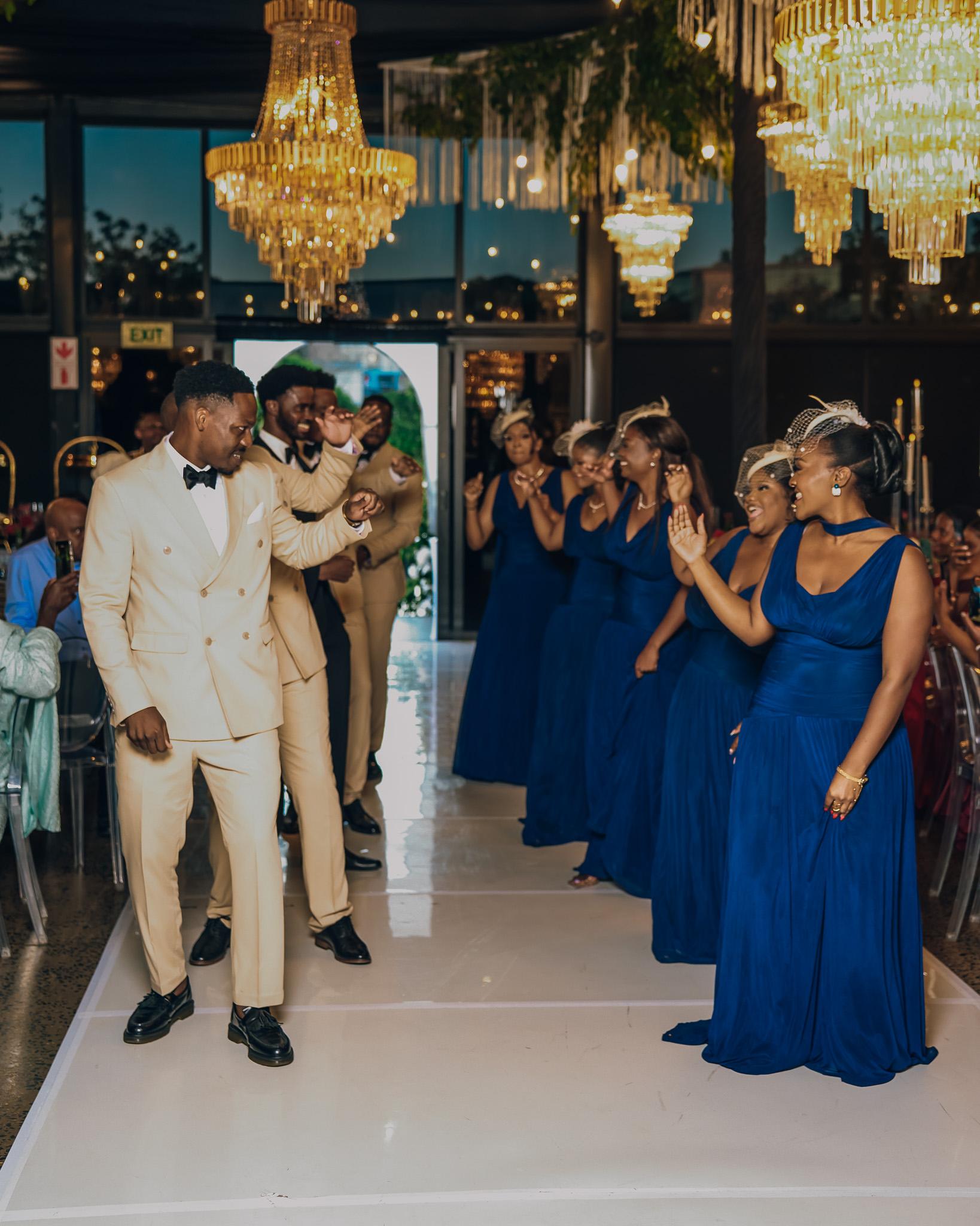 Wedding party celebrating together beneath the reception chandeliers.