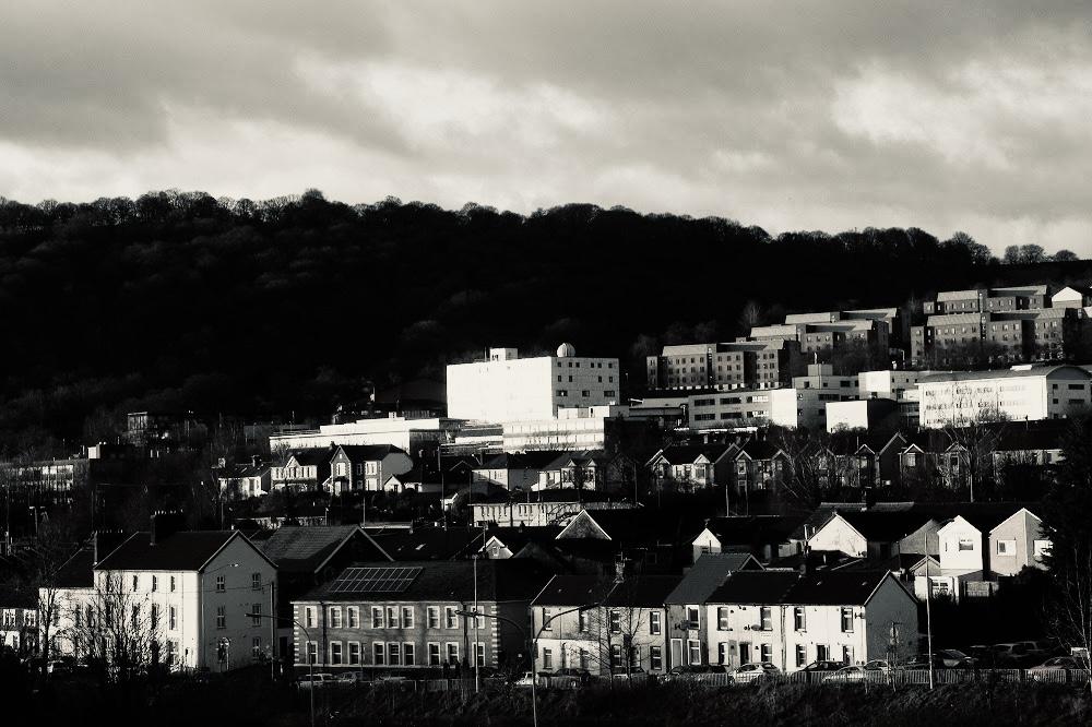 The University of South Wales Treforest campus and terraced houses set against a wooded hillside, in black and white